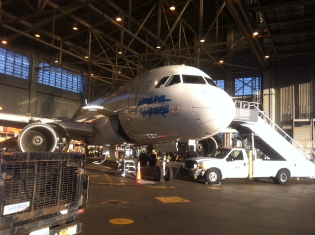 A large airplane parked inside a hangar, accompanied by a service truck nearby.