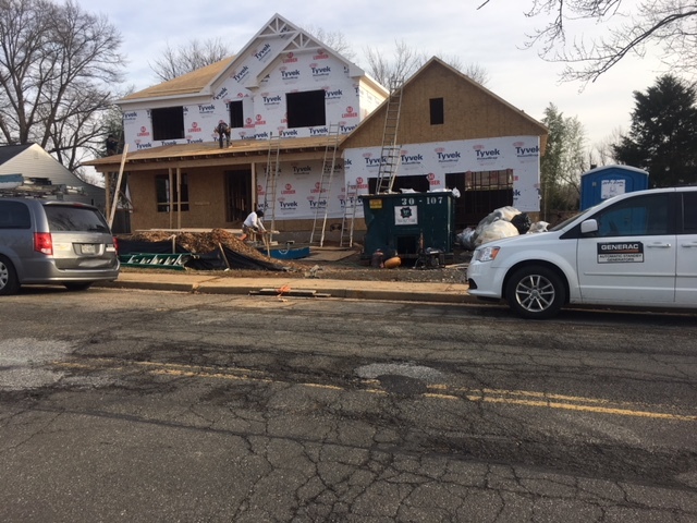 A house under construction with scaffolding, featuring a parked car in front on a clear day.